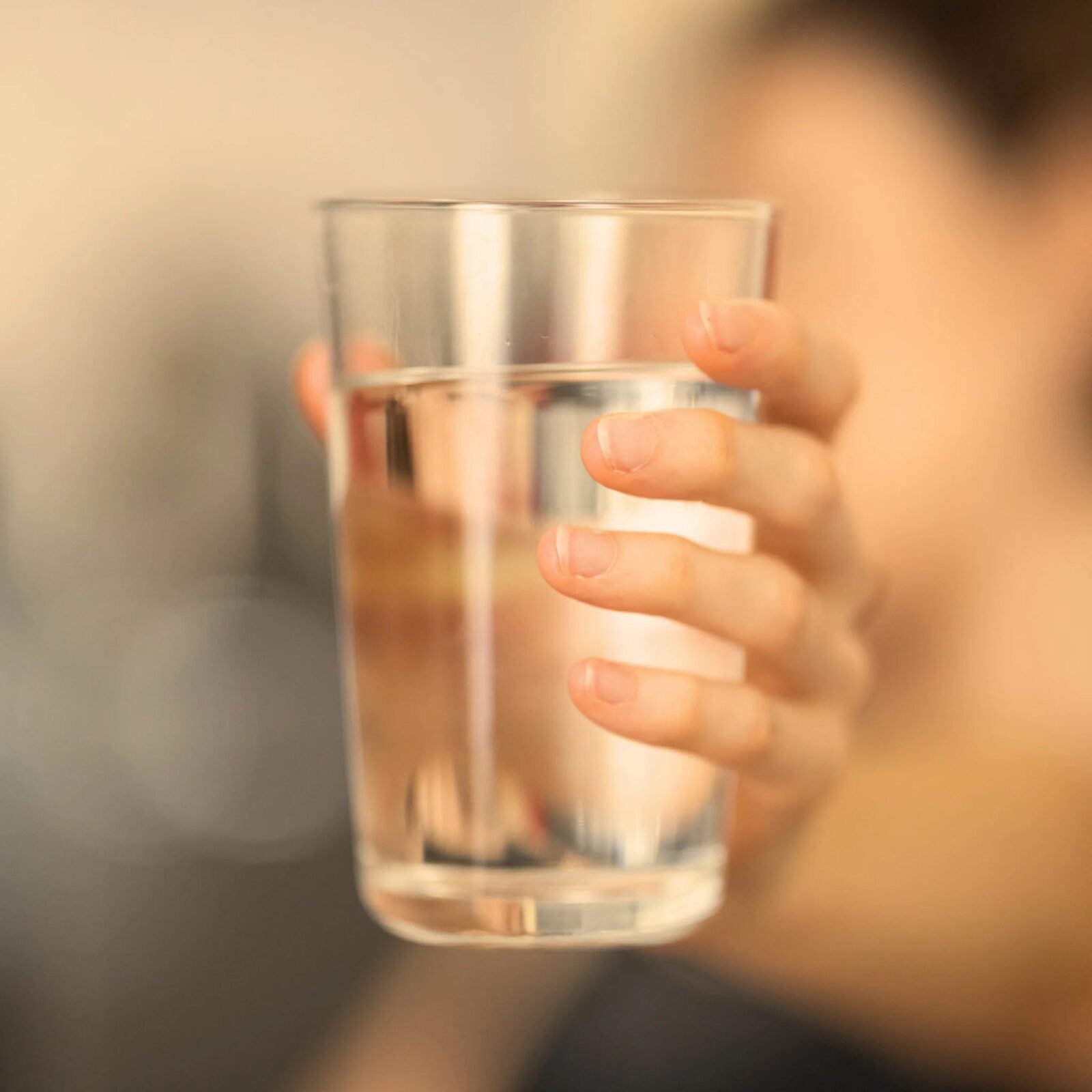 A hand offering a glass of water